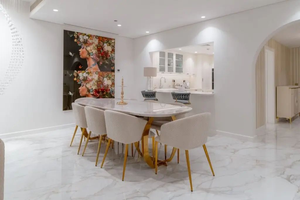 Modern dining and kitchen area after home remodeling in a Dubai apartment, featuring marble flooring and artistic wall décor.